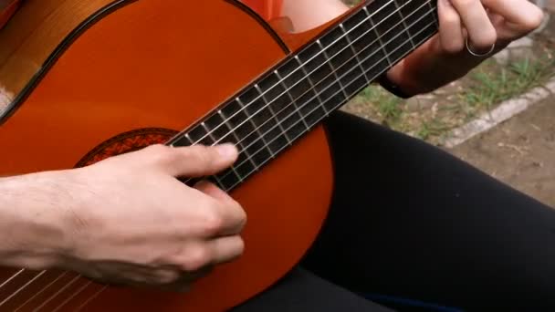 Výkonný hudebník. Kytarista hraje s prsty na akustickou dřevěnou kytaru. Venku. Close-up. - Záběry, video