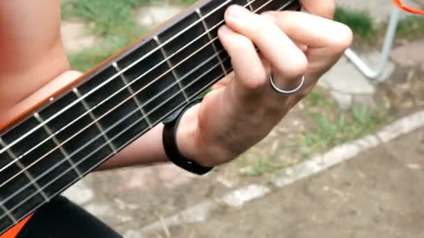 Músico de performance. Guitarrista toca con los dedos en una guitarra acústica de madera. Al aire libre. Primer plano
. - Metraje, vídeo