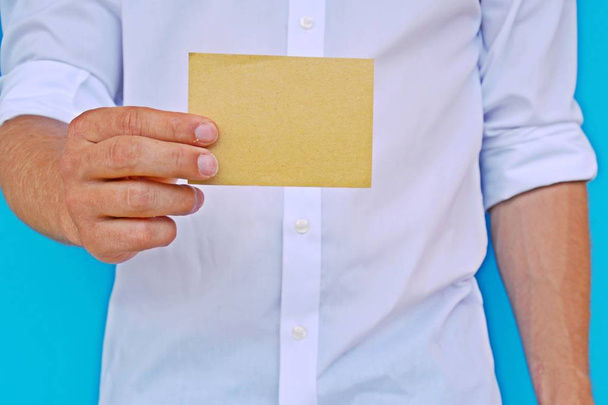 Hombre con camisa muestra una tarjeta en blanco de papel
 - Foto, Imagen