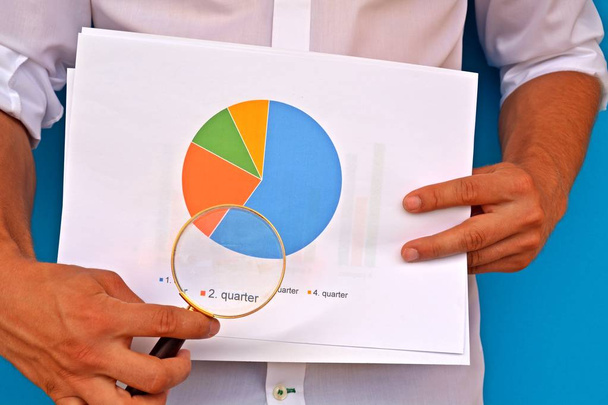 Mann im Hemd zeigt mit Lupe auf Statistik - Foto, Bild