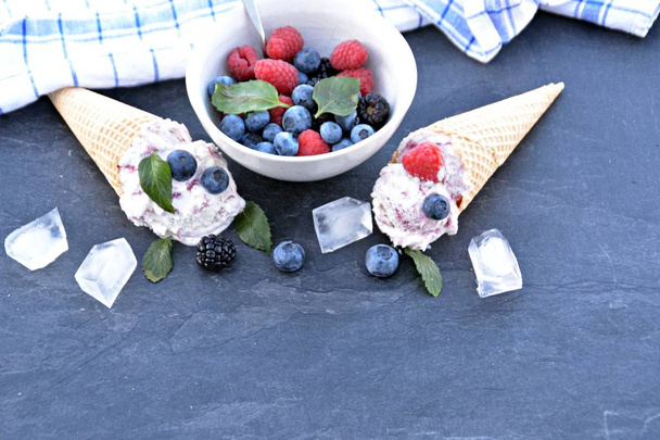  Vaflové zmrzlinové kornouty plněné lesními ovocnými kuličkami s čerstvými plody a mátovou na povrchu tmavého mramoru-koncept pro chladné letní dobrodružství s výbornou ovocnou zmrzlinou - Fotografie, Obrázek