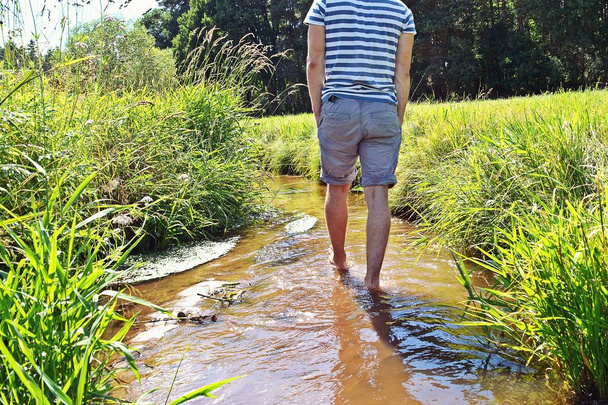 Zblízka na nohou se pomalu prochází nohama do malého rybníka s rostlinami, aby se osvěžit z teplého letního dne  - Fotografie, Obrázek