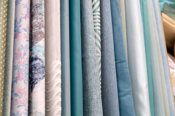 Close-up rijen van stukjes stof gemaakt van katoen, polyester, tapijt en andere materialen van verschillende kleuren en prints voor het naaien van gordijnen, beddengoed en kleding - Foto, afbeelding