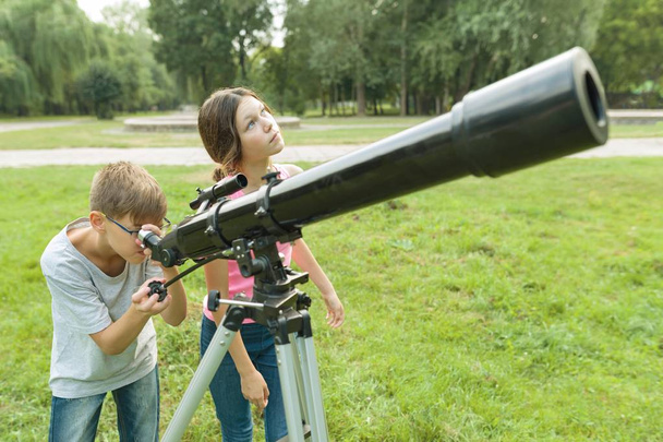 Children teenagers in the park looking through a telescope - Φωτογραφία, εικόνα
