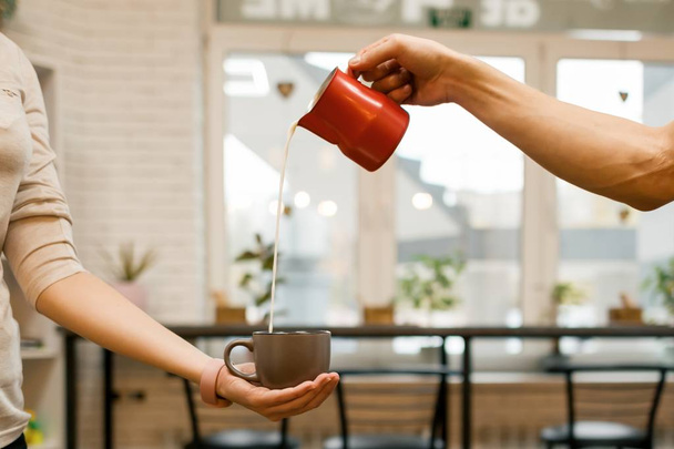 Closeup of pouring steamed milk into coffee cup, coffee shop background - Zdjęcie, obraz