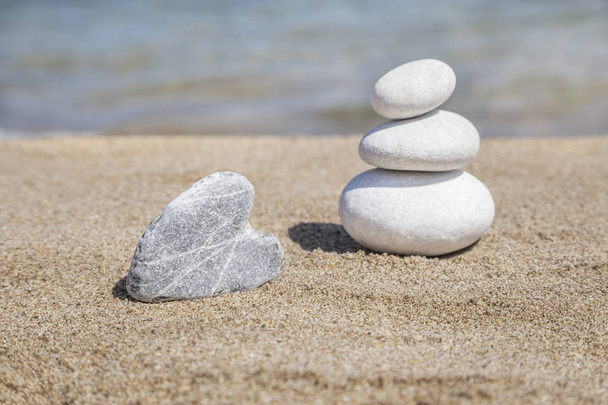 Камень в форме сердца и стопка гальки на балансе на песчаной косточке
 - Фото, изображение