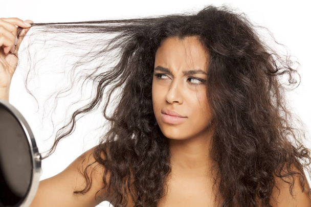 portrait of a unhappy young dark-skinned woman with messy long hair on a white background - Photo, Image