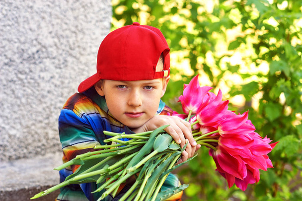 Portrait of a boy with flowers . A child holds a bouquet of tulips - 写真・画像