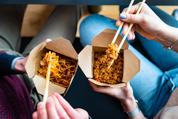 couple eating food packed in take-away box with chopsticks - Foto, imagen