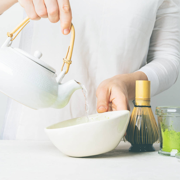 Close view of woman pouring water from teapot to make organic green tea Matcha - 写真・画像