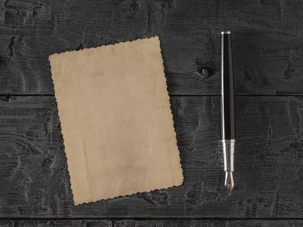Ένα κομμάτι παλιό χαρτί και μια πένα σε ένα ξύλινο τραπέζι. Ρετρό χαρτί γραφής. Επίπεδη ωοτοκίδα. - Φωτογραφία, εικόνα