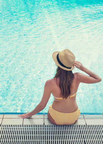 Young woman relaxing in swimming pool - Fotoğraf, Görsel