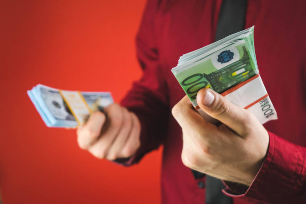 un hombre con una camisa roja con una tarjeta sostiene en su mano un fajo de billetes sobre un fondo rojo
 - Foto, imagen