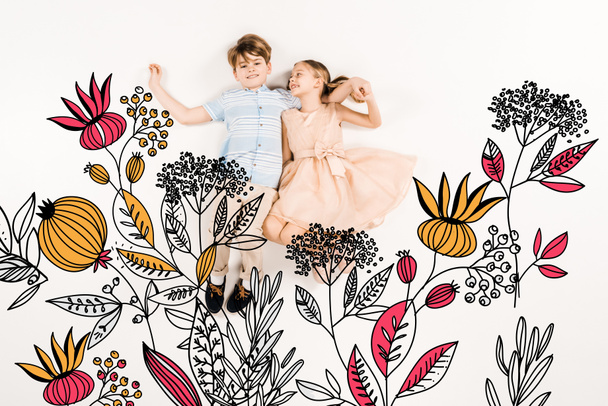 cheerful kid looking at happy friend and lying near flowers on white  - Foto, immagini