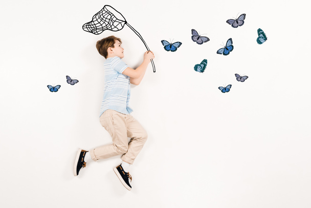 top view of cheerful kid holding butterfly net near butterflies on white  - Photo, Image