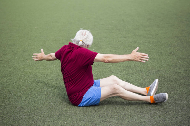 Ανώτερος άνθρωπος άσκηση σε ένα ανοιχτό γήπεδο - Φωτογραφία, εικόνα