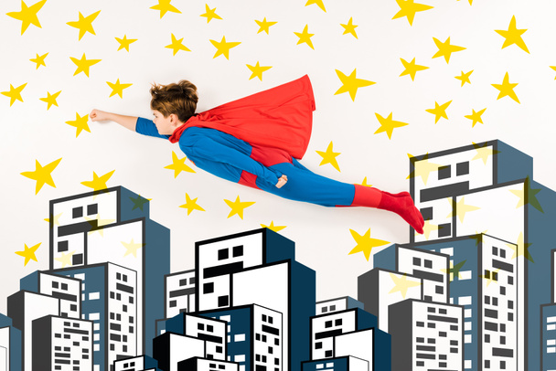 top view of kid in super hero costume flying near stars and buildings on white  - Photo, Image