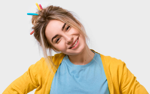 Aantrekkelijke Kaukasische jonge vrouw in gele blouse en blauw t-shirt, met kleurrijke markeringen op het haar, glimlachend breed en op zoek naar de camera, geïsoleerd over witte achtergrond. Mensen emoties - Foto, afbeelding