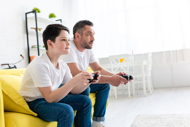 father and son playing Video Game on couch in Living Room with copy space - Foto, imagen