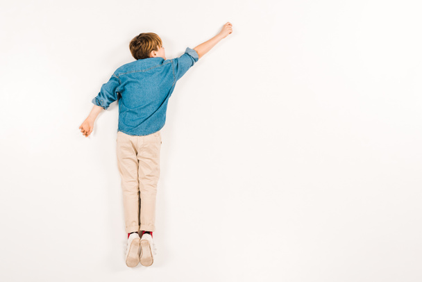 top view of kid lying and gesturing on white  - Foto, afbeelding