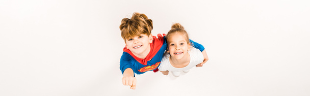 plan panoramique d'enfant heureux en costume de super héros étreignant ami et geste sur blanc
  - Photo, image
