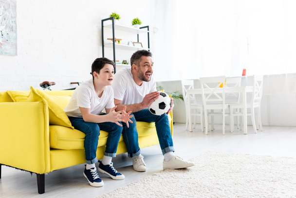 excited father and son watching sports match on couch at home with copy space - Фото, зображення