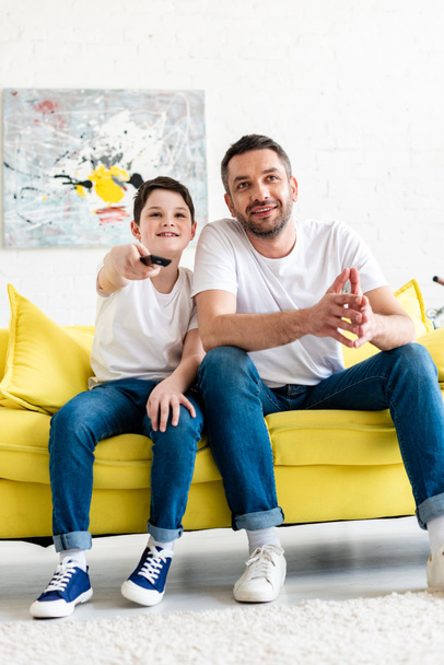 father and son sitting on couch and watching tv at home - Photo, Image