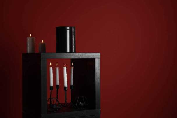 Urne mit brennenden Kerzen auf farbigem Hintergrund - Foto, Bild