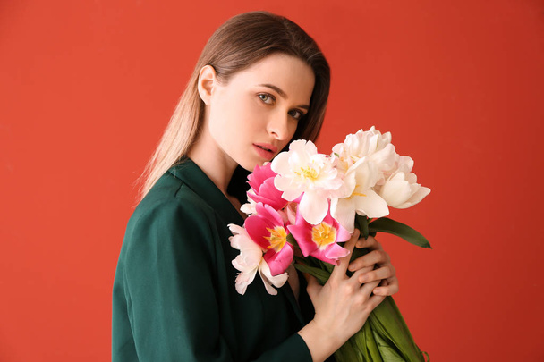 Young woman with bouquet of beautiful tulips on color background - Fotó, kép