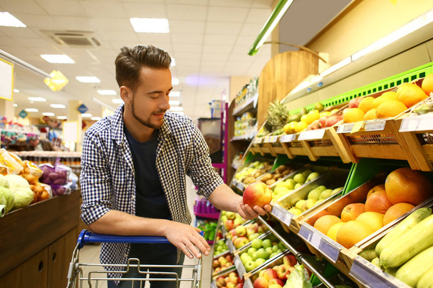 Young man choosing food in supermarket - 写真・画像