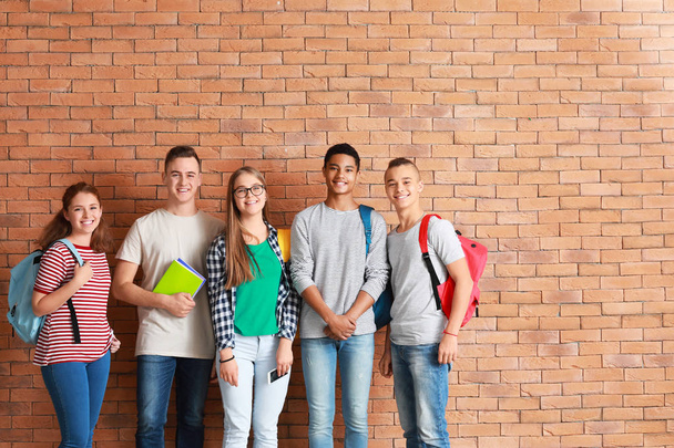 Grupo de adolescentes perto da parede de tijolo
 - Foto, Imagem
