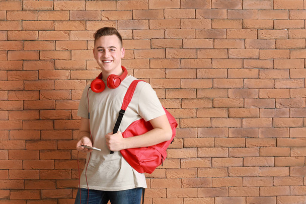 Cute teenage boy near brick wall - 写真・画像