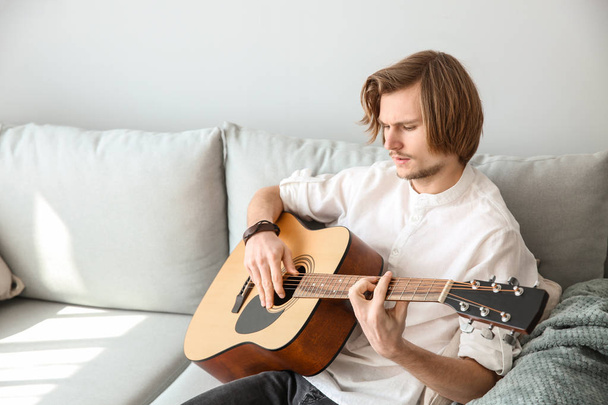 Handsome young man playing guitar at home - Photo, image
