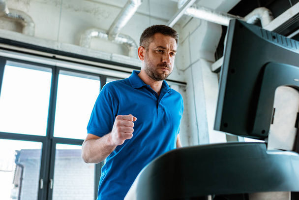 handsome man running on treadmill at gym - Photo, Image