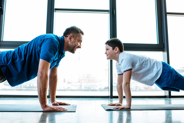 père et fils regardant les uns les autres tout en faisant pousser l'exercice à la salle de gym
 - Photo, image