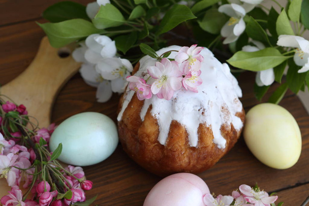 Easter cake and painted eggs surrounded by flowers - Фото, изображение