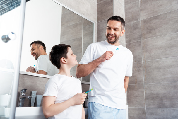 happy father and son brushing teeth in bathroom - 写真・画像