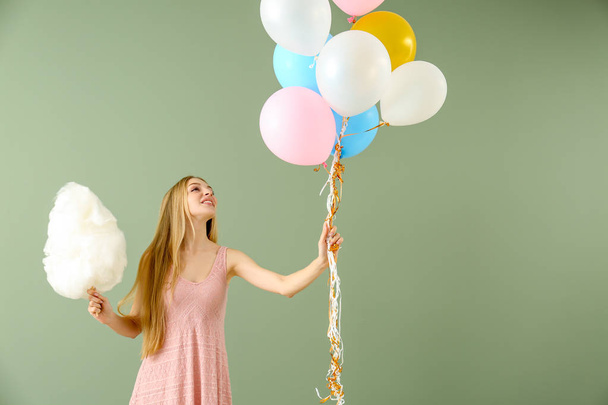 Beautiful woman with cotton candy and air balloons on color background - Фото, изображение