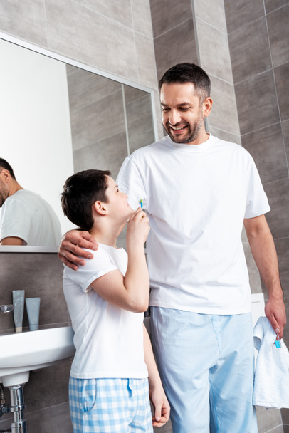 hymyilevä isä ja poika hammasharjat kylpyhuoneessa
 - Valokuva, kuva