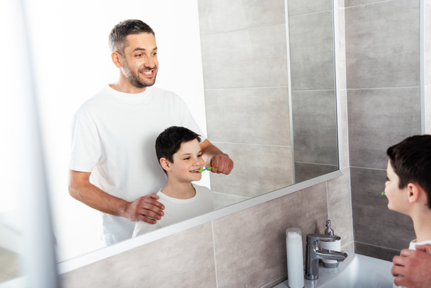 Ojciec szczotkowanie zębów syna w łazience podczas porannej rutyny - Zdjęcie, obraz