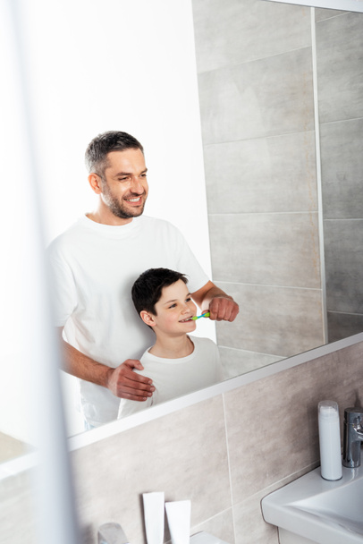 Ojciec szczotkowanie zębów syna w łazience podczas porannej rutyny - Zdjęcie, obraz