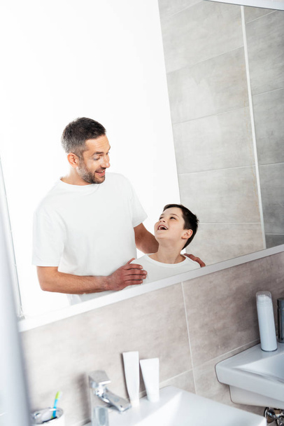 красивый отец обнимает сына в ванной комнате во время утренней рутины
 - Фото, изображение