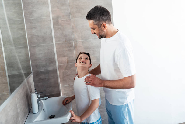 father embracing smiling son in bathroom during morning routine - Foto, Imagem