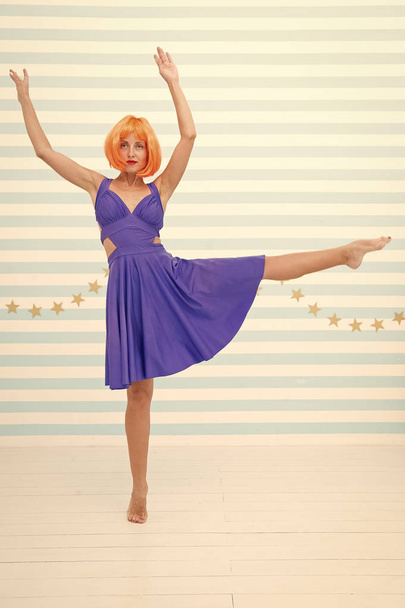 Fun and entertainment. Girl bob wig posing striped background of studio. Create your own mood. Lady red or ginger wig posing in blue dress. Comic and humorous concept. Woman playful mood having fun - Photo, image