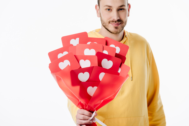 hyvännäköinen hymyilevä mies, jolla on kimppu punaista paperia leikattuja kortteja, joissa on sydänsymboleja ja jotka katsovat kameraa, joka on eristetty valkoisella
 - Valokuva, kuva