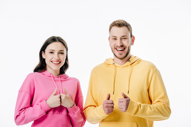 young cheerful man and woman showing thumbs up while looking at camera isolated on white - Zdjęcie, obraz