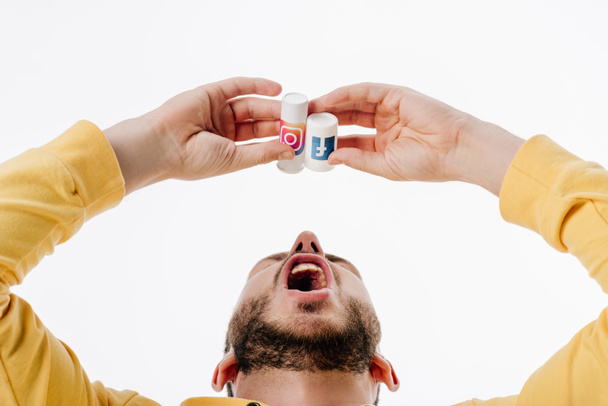 young man imitating using pills from container with facebook and instagram logos isolated on white - Photo, image