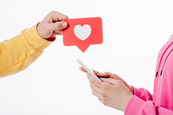 kalp sembolü ve beyaz izole akıllı telefon kullanarak kadın ile kırmızı kağıt kesme kartı tutan adam kırpılmış görünümü - Fotoğraf, Görsel