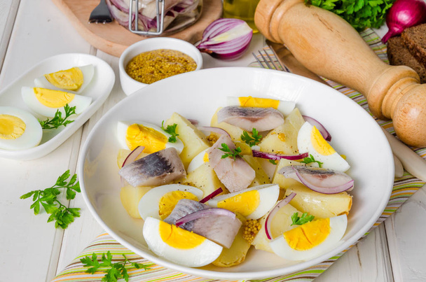 Potato salad with salted fish, boiled eggs, onions and parsley leaves. - Foto, Imagen