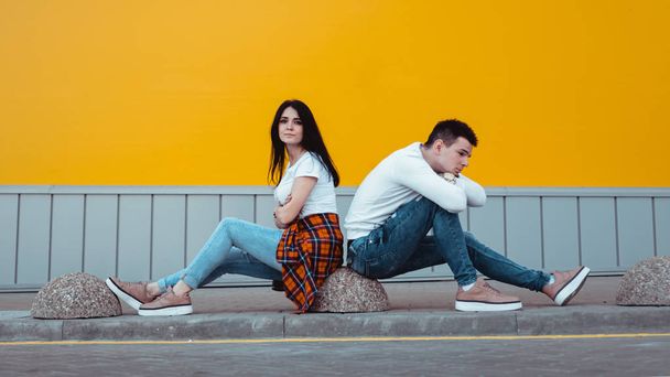 Confused young couple standing with one anothers back over yellow background - Photo, Image